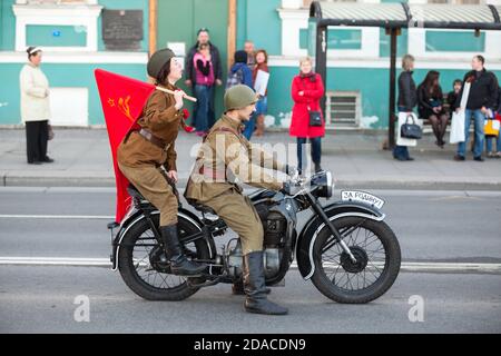 ST. PETERSBURG, RUSSLAND-9. MAI 2015: Sowjetische loldier mit Frau gekleidet Militäruniform Fahrt auf Oldtimer-Motorrad im Zentrum der Stadt. Feier des Th Stockfoto