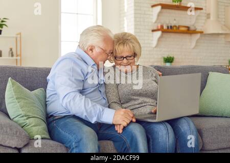 Liebevolle ältere Paar kommunizieren oder etwas online bestellen auf Laptop Zu Hause Stockfoto