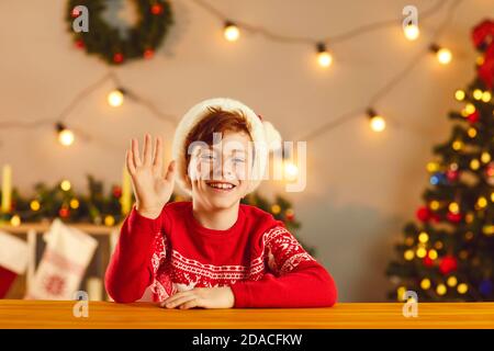 Fröhlicher Junge lächelt und winkende Hand sagen Hallo während Video Anruf oder Weihnachten Live-Stream Stockfoto