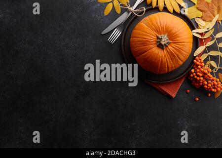 Thanksgiving Dinner Konzept. Herbstblätter und Kürbisse auf schwarzem texturierten Hintergrund Stockfoto