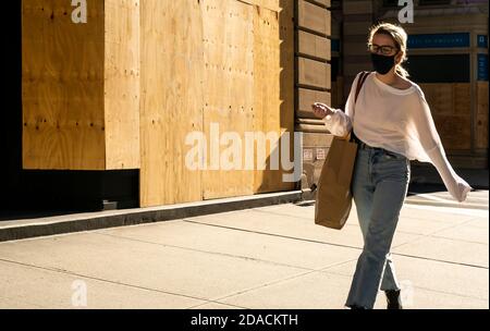 Maskierte Fußgänger gehen am Mittwoch, den 4. November 2020, in Manhattan in New York an der Schaufenster vorbei (© Richard B. Levine) Stockfoto