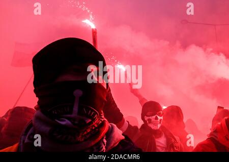 Warschau, Polen. November 2020. Maskierte Demonstranten verbrennen während eines Unabhängigkeitsmarsches in Warschau rote Fackeln. Rechtsextreme Sympathisanten haben am Mittwoch in der Nähe des polnischen Nationalstadions, das vor kurzem in ein COVID-19-Feldkrankenhaus umgewandelt wurde, gegen Ende eines unabhängigkeitstages, der unter Missachtung der Pandemiebeschränkungen stattfand, mit der Polizei zusammengeschlagen. Kredit: Grzegorz Banaszak/ZUMA Wire/Alamy Live Nachrichten Stockfoto