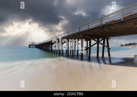 Malibu Pier Strand mit Bewegungsunschärfen und Sturmhimmel in der Nähe von Los Angeles in Südkalifornien. Stockfoto