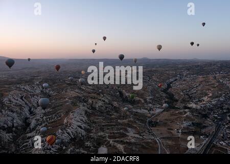 Heißluftballons schweben bei Sonnenaufgang über der Felsformationen Landschaft von Kappadokien, Türkei Stockfoto