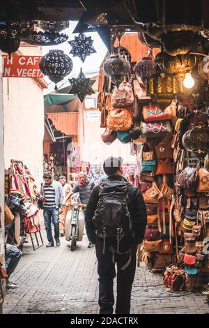 Marrakesch, Marokko - APRIL 26 2019: Blick auf einen Touristen, der ein Geschäft mit vielen Produkten auf einer belebten Straße in Medina sucht Stockfoto