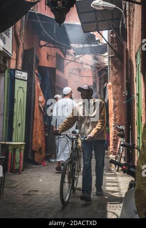 Marrakesch, Marokko - APRIL 26 2019: Blick auf einen schwarzen Maroccan und sein Fahrrad auf einer Straße von Medina bei Tageslicht Stockfoto