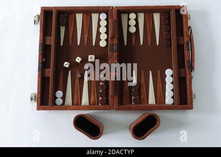 Ein Backgammon-Set, das für zwei Personen auf weißem Hintergrund gespielt werden kann. Stockfoto