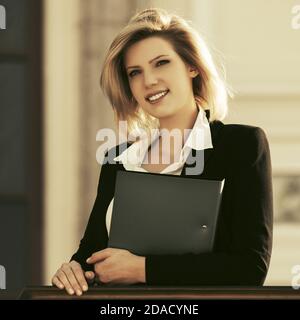 Glückliche junge Geschäftsfrau mit einem Ordner im Büro gebäude Stilvolle Mode Modell im schwarzen Anzug Jacke Stockfoto