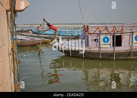 Varanasi, Indien, November 2015. Ein Mann nähert sich seinem Boot mit einem Ruder zu einem Ghat am Ganges. Stockfoto