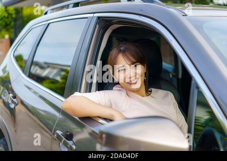 Asiatische glücklich junge schöne Frau fahren ein Auto in Vordersitz mit Lächeln bereiten Sie sich auf die Reise mit ihrem Auto. Stockfoto