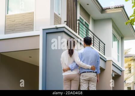 Porträt des jungen asiatischen Paares, das zusammen steht und umarmt und vor ihrem neuen Haus glücklich aussieht, um neues Leben zu beginnen. Familie, Alter, Zuhause, echte Esta Stockfoto