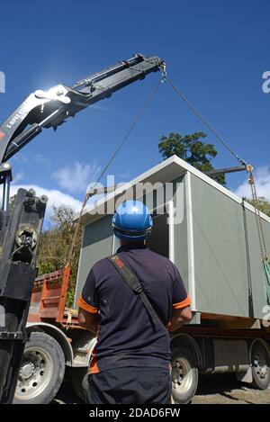 GREYMOUTH, NEUSEELAND, 21. OKTOBER 2020: Ein Kranführer arbeitet daran, ein kleines Gebäude von einem LKW auf seine Pfeiler zu heben. Stockfoto