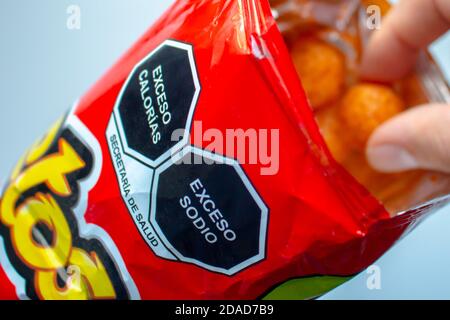 Calgary, Alberta. Kanada. November 11 2020. Nahaufnahme einer hohen Natrium-und Kalorien Warnschilder auf einem Beutel mit cheetos und eine Person essen. Stockfoto