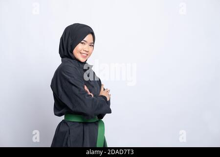 Frau in Hijab in pencak silat Uniform Posen gekreuzte Hände Mit Copyspace im isolierten Hintergrund Stockfoto