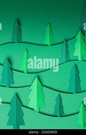 3D Pop out Weihnachtsbäume Papier Kunstwerk in grünem Hintergrund. Weihnachtsbaum Papier schneiden Design-Karte. Draufsicht. Flach liegend Stockfoto