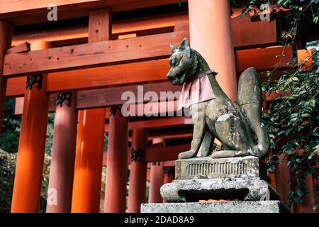 Fuchsskulptur mit roten Torii-Toren am Fushimi Inari Taisha-Schrein in Kyoto, Japan Stockfoto