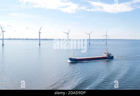 Containerschiff, das Windturbinen im Meer passiert Stockfoto