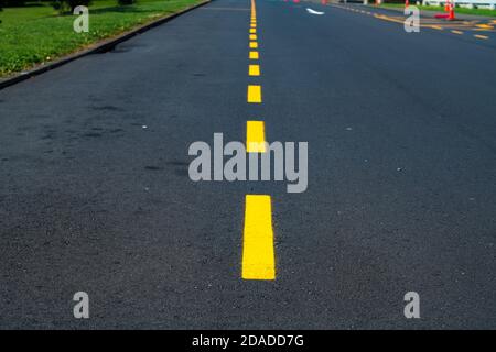 Nahaufnahme eines gelben Trennstreifens auf einer asphaltierten Straße Stockfoto