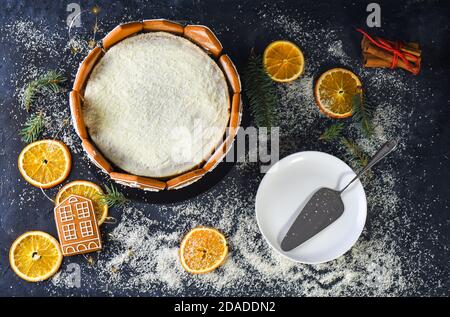 Schöner und köstlicher Kekskuchen mit getrockneten Orangen, Zimtstangen, Tannenstäbchen, Utensilien, Lebkuchen in Form von Häusern. Festlicher Kuchen. Flach Stockfoto