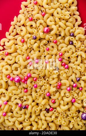 Pasta mit Kugeln auf rotem Hintergrund dekoriert. Blick von oben Stockfoto