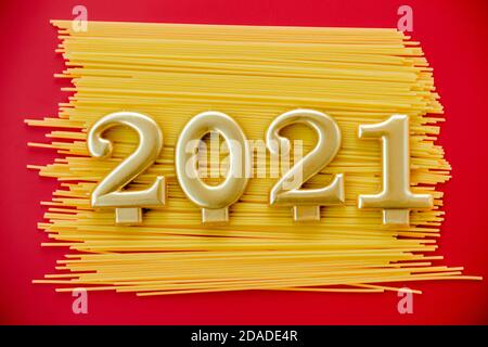 Frohes Neues Jahr 2021. Symbol aus Nummer 2021 und Makkaroni auf rotem Hintergrund Stockfoto
