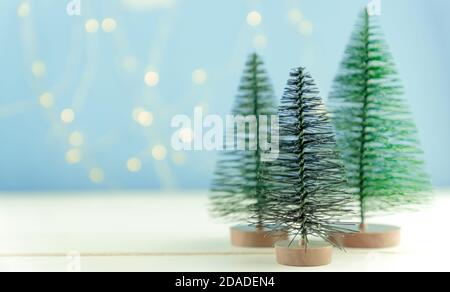 Miniatur Spielzeug Weihnachtsbäume auf einem Holztisch mit Schnee. Imitierte realistische Szene Stockfoto