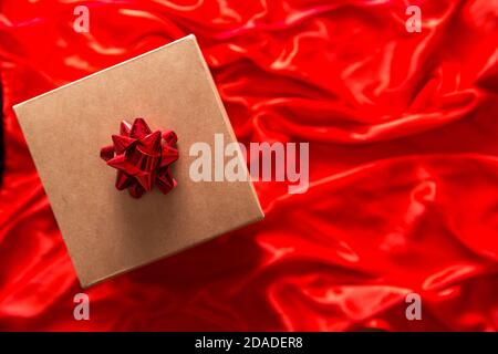 Geschenk in Bastelverpackung auf rotem Seidenhintergrund Stockfoto