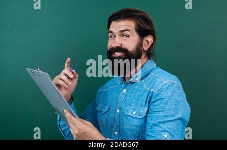 Gut aussehender Mann mit Bart und Schnurrbart zeigt Dokumentpapier für Notizen, Überprüfung der Ergebnisse. Stockfoto