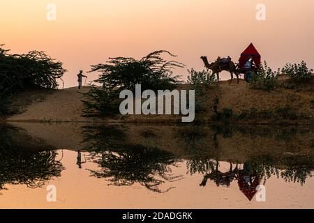 Spiegelung eines Kamelkarren und eines Mannes im Wasser. Stockfoto