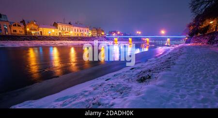 uzhhorod, ukraine - 26 DEC, 2016: Altstadt in einer weihnachtsnacht. Schöne Stadtlandschaft am Fluss. Schnee am Ufer. Brücke und Laternen glühen Stockfoto