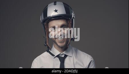 Selbstbewusst lächelnder Geschäftsmann trägt einen Motorradhelm, Schutz und Sicherheitskonzept Stockfoto