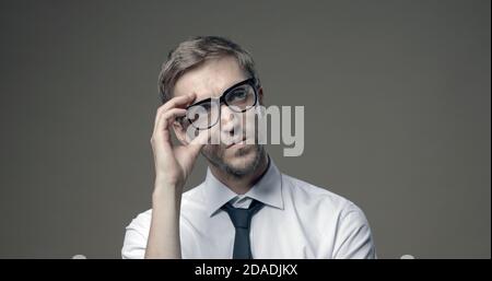 Hübscher junger Geschäftsmann posiert und passt seine Brille an Stockfoto