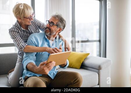 Glücklich lächelnd reifes Paar mit digitalen Tablet zu Hause Stockfoto