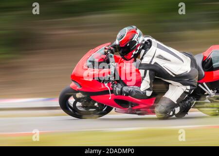 Motorrad-Praxis lehnt sich in eine schnelle Ecke auf der Strecke Stockfoto