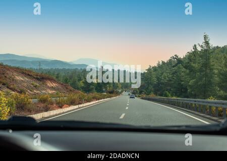 Blick aus dem Auto. Auto fahren. Blick von der Windschutzscheibe eines Autos auf einer Straße bei Sonnenuntergang. Stockfoto