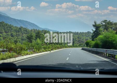 Blick vom Auto auf die Straße. Blick in sich bewegende Autostraße. Reisen mit dem Auto. Schöne Aussicht auf die Landschaft aus dem Auto Stockfoto