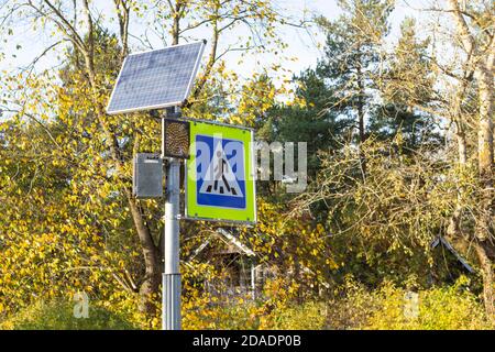 Fußgängerübergangsstraßenschild und solarbetriebene Ampel. Stockfoto