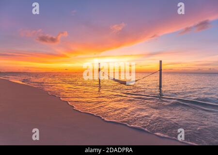 Tropischer Sonnenuntergang Strand Hintergrund als Sommerlandschaft Panorama mit Strand Schaukel Hängematte und weißem Sand und ruhigen Meer Strand Banner. Perfekte Strandszene Stockfoto