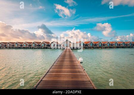 Sonnenuntergang auf der Insel der Malediven, luxuriöse Wasservillen-Bungalows. Steg mit Wolken am Sonnenuntergang. Sonnenuntergang auf den Malediven. Wasserbungalows Resort am Inselstrand Stockfoto