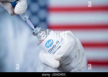 Maski, Indien - Nov 12,2020 : Arzt hält Pfizer BioNTech-Impfstoff und Spritze gegen Coronavirus COVID-19-Krankheit mit US-Flagge als zu schützen Stockfoto