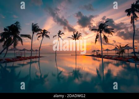 Luxus Resort Strand. Wunderschöner Pool und Sonnenuntergang. Luxuriöse tropische Strandlandschaft, Liegestühle und Sonnenliegen Infinity Pool Wasserspiegelung. Stockfoto