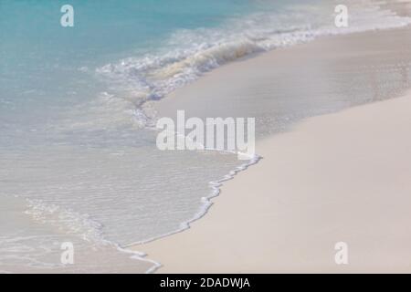 Blaue Ozean Wellen Sonnenlicht Reflexion Sand Strand Hintergrund. Ruhige Wellen auf weißem Sand, sonniges tropisches Wetter, sommerliche Stimmung Stockfoto