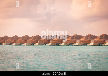 Sonnenuntergang auf der Insel der Malediven, Luxus-Wasservillen-Resort und hölzerner Pier. Schöner Himmel und Wolken und Strand. Toller Sommerurlaub, Aussicht zum Entspannen Stockfoto