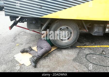 Asian Mechaniker unter LKW Reparatur schmutzig fettigen Motor mit Problem Stockfoto
