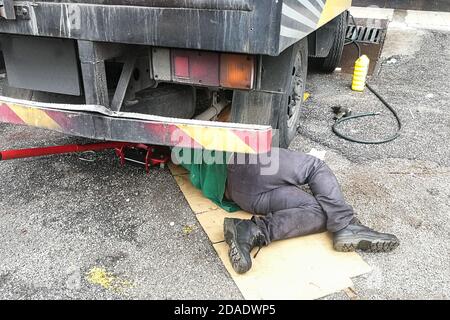 Asian Mechaniker unter LKW Reparatur schmutzig fettigen Motor mit Problem Stockfoto