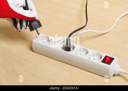 Nahaufnahme eines Elektrikers, der Verlängerungskabel miteinander einsteckt. Mans Hand Stecker Verlängerungskabel Stockfoto