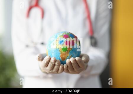 Die Hände der Ärztin in Handschuhen halten den Globus. Stockfoto