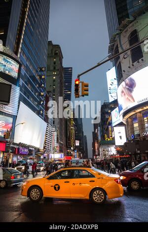 NEW YORK, USA - 30. April 2016: Kreuzung von 7 AV und W 42nd St an einem regnerischen Abend. Lichter und Schatten von NYC. Lichter der Werbung auf Straßen von Stockfoto