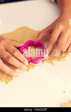 Granchild mit Formschneider für Teig am weihnachtstag. Happy fröhlich freudig Teenager-Mädchen hilft älteren Frau Vorbereitung süße Kekse, um Winterferien zu feiern. Stockfoto