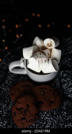Becher mit Marshmallows und Chocolate Chip Cookies auf dunkle Weihnachten Hintergrund mit Lichtern - vertikale Foto Stockfoto